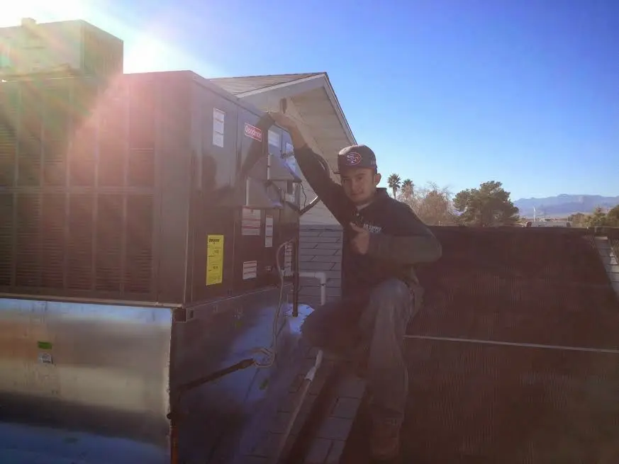 HVAC technician performing Boiler Repair on a rooftop unit in Bryan